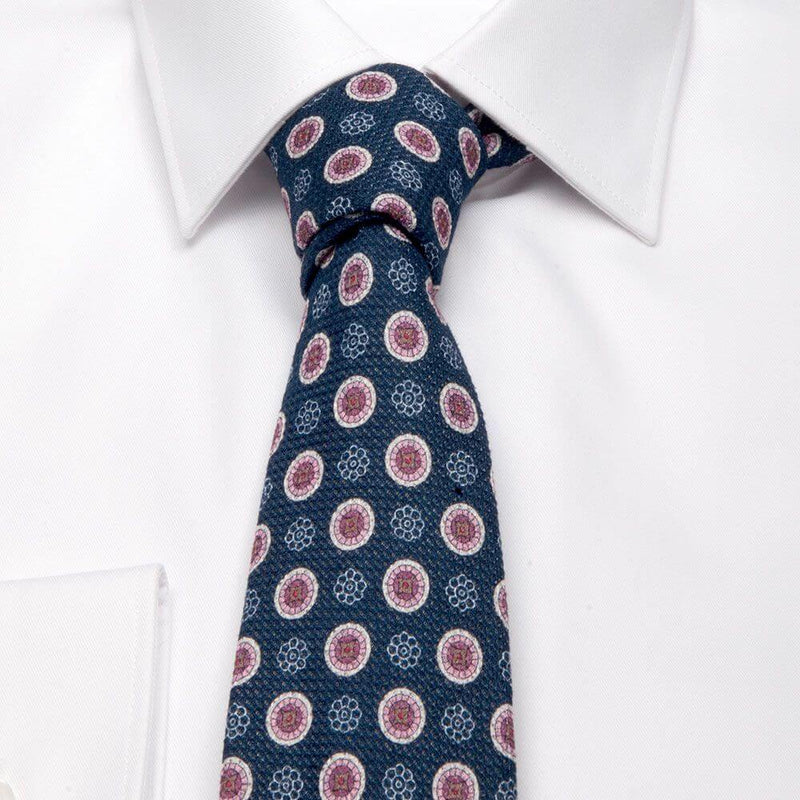 Dunkelblaue Giro Inglese-Krawatte mit Blüten-Muster von BGENTS am Hemd gebunden