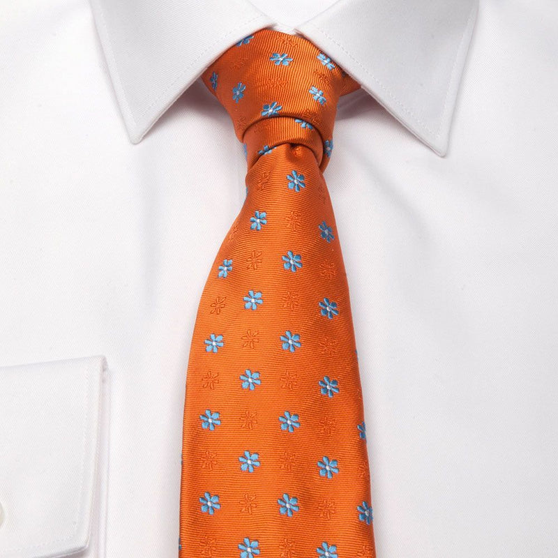 Seiden-Jacquard Krawatte in Orange mit hellblauen Blüten-Muster am Hemd gebunden